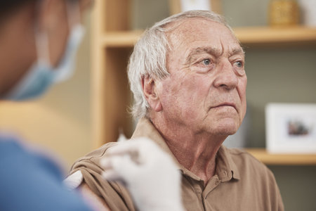 Needles are not his favourite thing. an unrecognizable nurse giving a patient the vaccine at home.