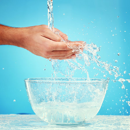 Water bowl, health and hands splash liquid for hygiene, cleaning and wellness beauty routine with mockup. Water splash container, skincare and wet palm of self care man isolated on blue backgroundの写真素材