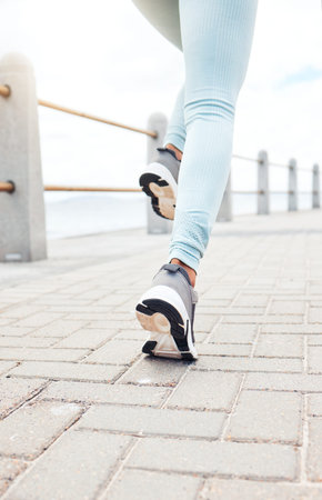 Zoom of runner, sport woman for fitness legs running, training or exercise workout by the sea, beach...