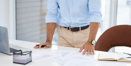 Working through a new budget for the quarter. Closeup shot of an unrecognisable businessman going through paperwork in an office.の写真素材
