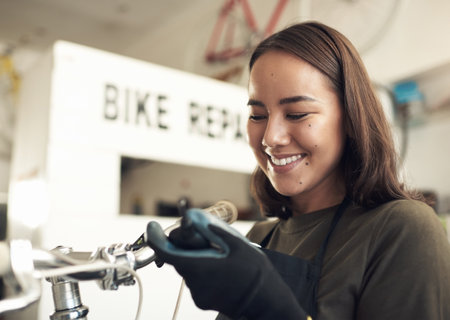 Each bike has their own journey to share. an attractive young woman standing alone in her shop and repairing a bicycle.の写真素材
