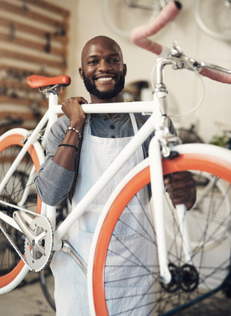Do you even lift bro. Portrait of a young man lifting a bicycle up at work.