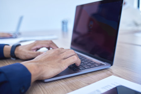 Completing deadlines with ease and on time. Closeup shot of an unrecognisable businessman working on a laptop in an office.の写真素材