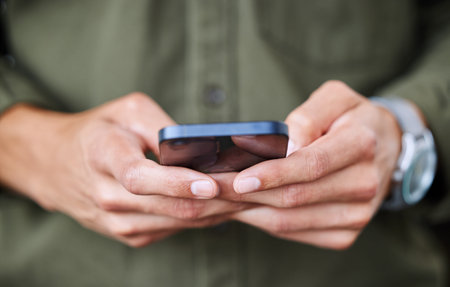 Reading notifications as they pop up on his phone. Closeup shot of an unrecognisable man using a...