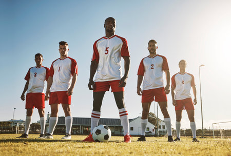 Soccer player, team and sports training on soccer field by men standing with ball, power and strong mindset. Football, fitness and man football players united in support on football field for workoutの写真素材