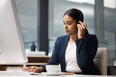 Managing the days inbound calls. a young businesswoman working on a computer in a call centre.の写真素材