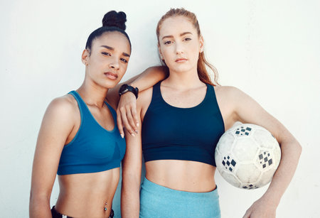 Soccer, women and portrait of friends with a ball standing by a white background for training. Fitness, football and girl athletes ready for a sports workout or exercise for a game together.の写真素材