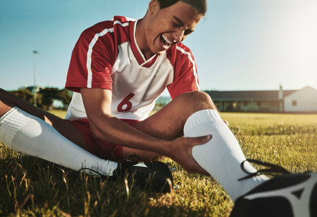 Man, soccer and sport leg injury suffering in pain, agony and discomfort during training match or game on the field. Male football player screaming holding painful area in sports accident on grassの写真素材