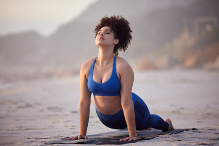 The better your practice, the brighter your flame. a young female doing yoga on the beach.の写真素材