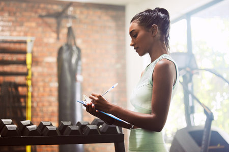 Fully equipped and ready for your fitness needs. a young woman doing inventory while working in a...