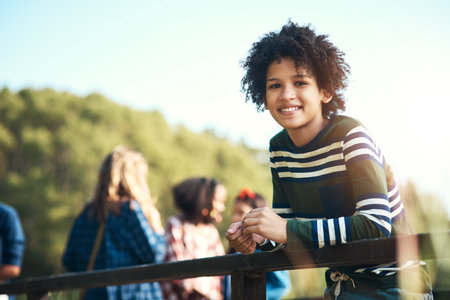 The weathers too good to sit inside. a teenager boy standing on a bridge in nature at summer camp.の写真素材