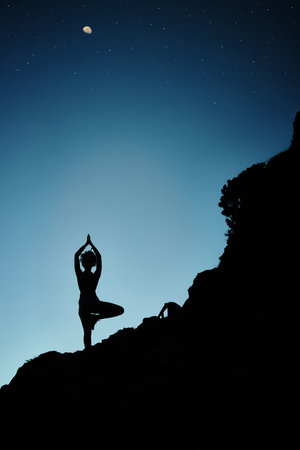 Seek and you shall find...Silhouette shot of a woman practising yoga outside at night.の写真素材