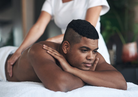 Not a care in the world. a young man getting a back massage at a spa.の写真素材