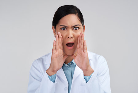 Scientist dont usually indulge in hearsay...Cropped portrait of an attractive young female scientist looking shocked in studio against a grey background.の写真素材