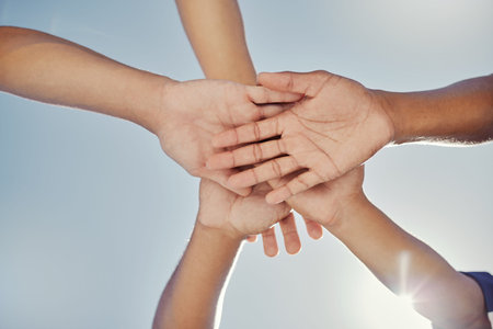 Hands, teamwork and collaboration, blue sky and low angle of baseball people working together for...