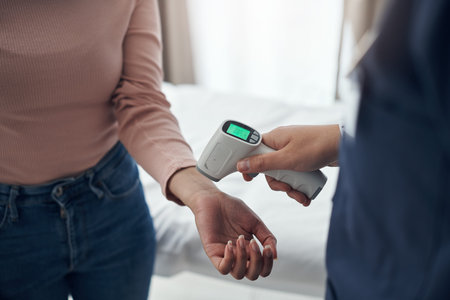 Regular temperature checks are crucial. an unrecognizable doctor using a thermometer to take a...