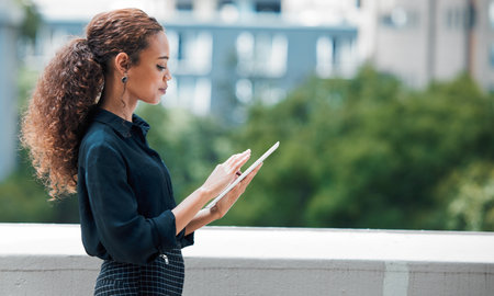 Who says you cant work from any location. a young businesswoman using a tablet against an urban background.の写真素材