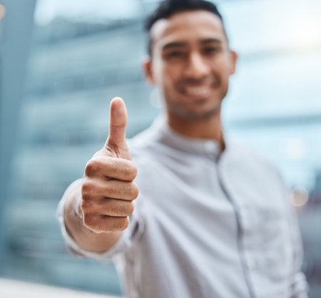 I know a winner when I see one. a young businessman showing thumbs up against an urban background.