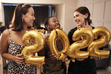 Were ready for the New Year. a diverse group of friends standing together and holding 2022 balloons during a New Years dinner party.の写真素材