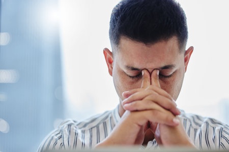 Breathe and recollect. a young businessman sitting alone in the office and suffering from a...