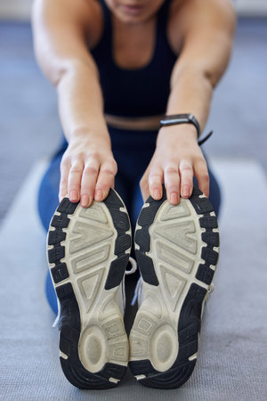Woman runner stretching, sports shoes and athlete touching toes on a yoga mat on floor for leg...