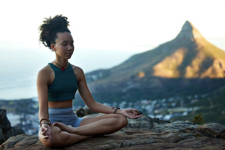 II get a good view and the perfect place to meditate. a young woman meditating while out in the...