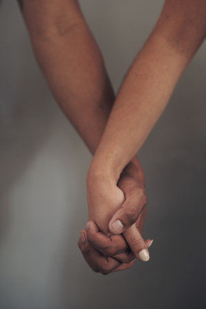 Were each others source of support. an unrecognizable couple standing together against a grey wall indoors and holding hands.の写真素材