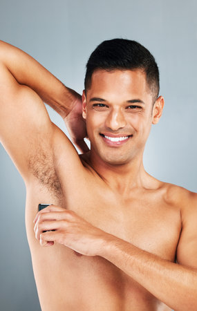 Man shaving armpit body hair for self care, hygiene and beauty skincare routine, wellness and epilation cleaning. Happy, smile and mockup portrait of young person grooming isolated on gray backgroundの写真素材