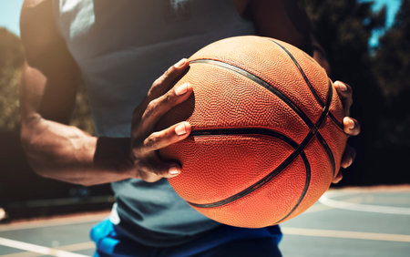 Basketball, basketball player and athlete hands closeup holding ball on basketball court in urban city park outside. African man, sports fitness and healthy lifestyle wellness training outdoorsの写真素材
