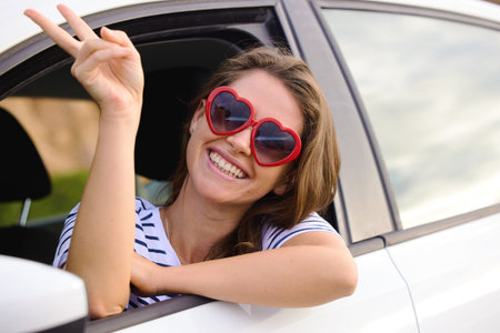 Boring days behind me, brighter days ahead. a young woman wearing showing a peace sign out of a car...