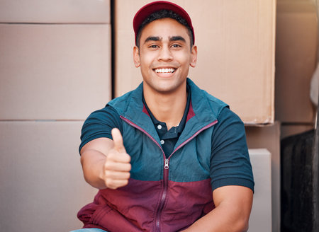 Delivery, thumbs up and courier man, shipping box and retail, ecommerce sales and service, employee smile in portrait. Success, worker in commercial distribution, working and supply chain business.の写真素材