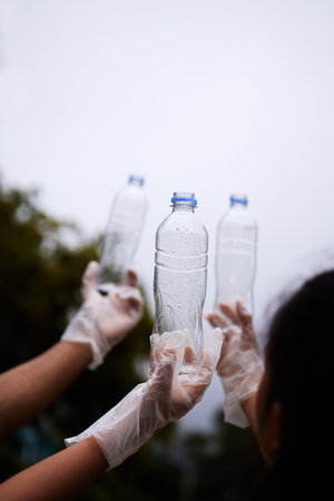 To be prepared is already half a victory. group of people holding up three empty plastic bottles with a sky background.の写真素材