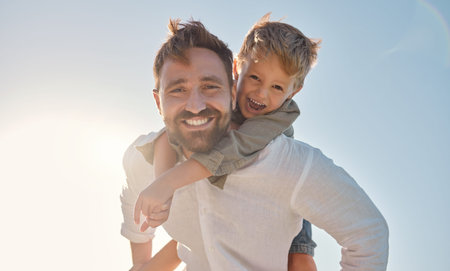 Family, portrait and father and son relax against a blue sky background, playing and having fun...