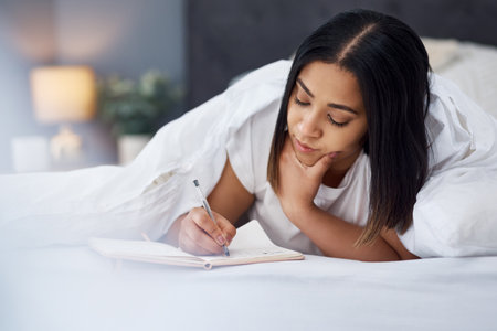 Today I feel like staying in bed. a young woman in bed at home.の写真素材