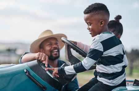Every boy remembers his first tractor ride. a mature man helping his adorable son and daughter ride...