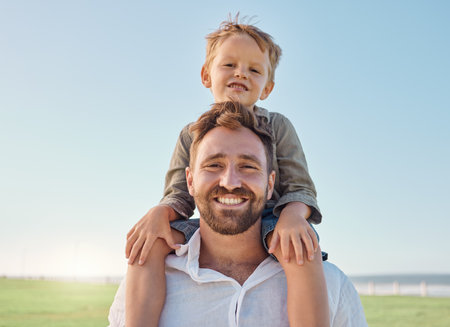 Family, father and child with smile at nature park for fun, relax and freedom with a blue sky. Portrait of happy man and playful boy kid outdoor for love, piggyback and bonding on a summer vacationの写真素材