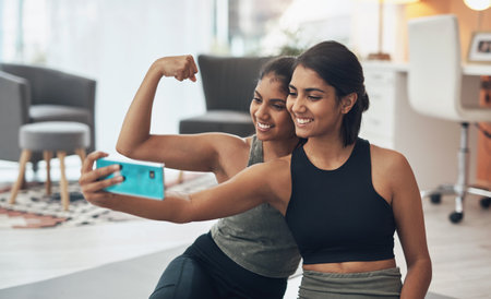 Youre always in a better mood after your workout. two young women taking a selfie while sitting at home in exercise clothes.の写真素材