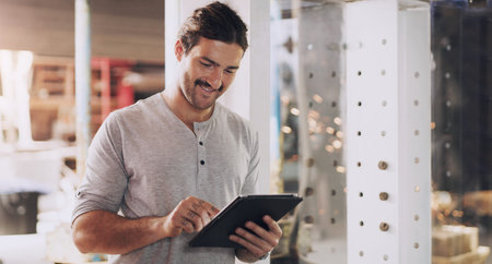 My work is trending online. a young man using a digital tablet in his workshop.