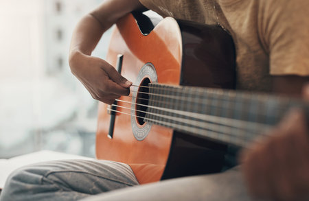 A guitar lesson is a gift that lasts a lifetime. an unrecognisable woman playing the guitar at home.