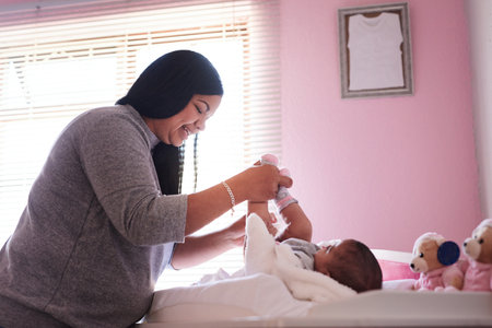 Anything a mother does is done with love. a young woman changing her baby girls clothing at home.の写真素材