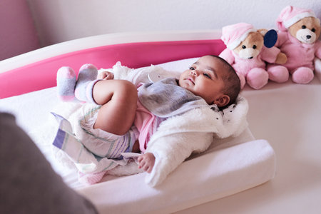 Life in the nursery is so much sweeter. a woman changing her baby girls clothing at home.の写真素材