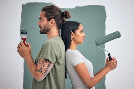 Paint, renovate and diy with a couple in their home for painting, redecorating or improvement. House, interior and room with a man and woman painting a wall in their apartment for renovationの写真素材