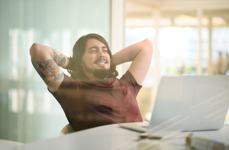 Hes such a pro at his job. a young businessman taking a break at his office desk.の写真素材