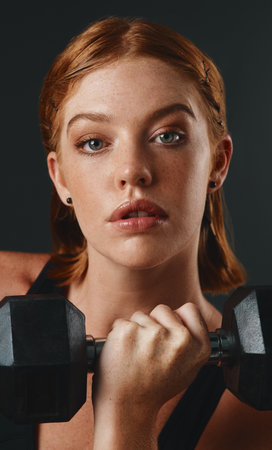 Break your bad habits. Studio portrait of a sporty young woman exercising with a dumbbell against a black background.の写真素材