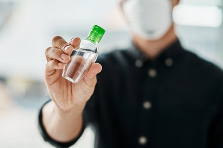 Get your hands on some of this. a young businessman wearing a mask and using hand sanitiser.の写真素材