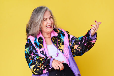 Unleash your inner rockstar. a cheerful and stylish senior woman posing against a yellow background.