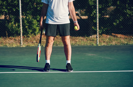 Keep calm and serve an ace. Closeup shot of an unrecognisable man holding a tennis racket and ball on a tennis court.の写真素材
