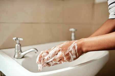 Scrub them til theyre squeaky clean. a woman washing her hands with soap in the bathroom sink at...