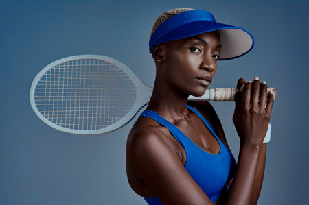 Im super proud of myself. Studio shot of a sporty young woman posing with a tennis racket against a grey background.の写真素材