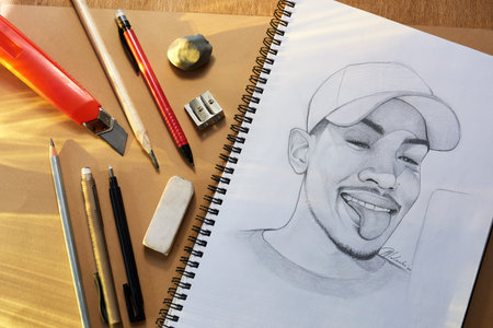 Some people keep diaries, I keep a sketchbook. a pencil drawing and other various artistic tools on a table.の写真素材